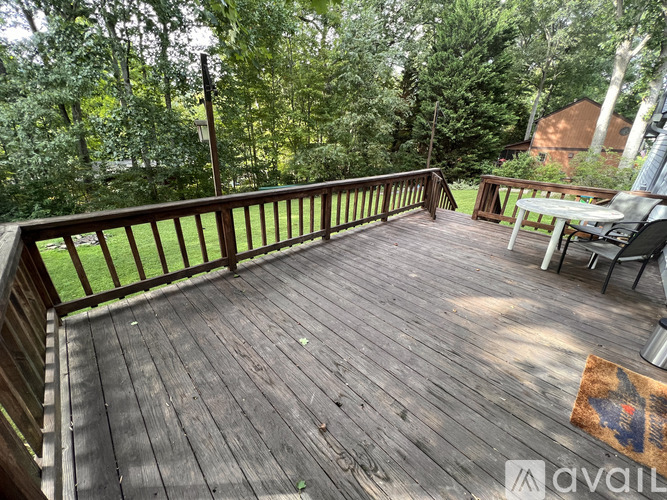 A wooden deck with a table and chairs overlooking a grassy area.