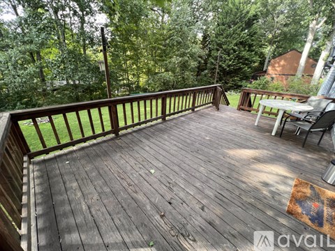 A wooden deck with a table and chairs overlooking a grassy area.