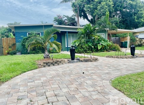 A brick walkway leads to a house with a blue exterior.