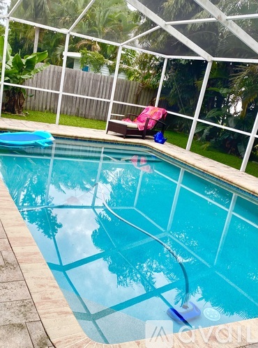 A small pool with a white fence and trees in the background.