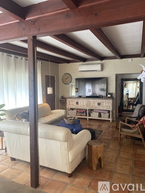 A living room with a white couch and wooden beams.