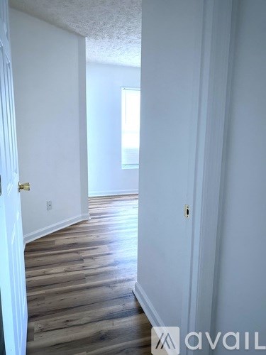 A hallway with wood flooring and white walls.