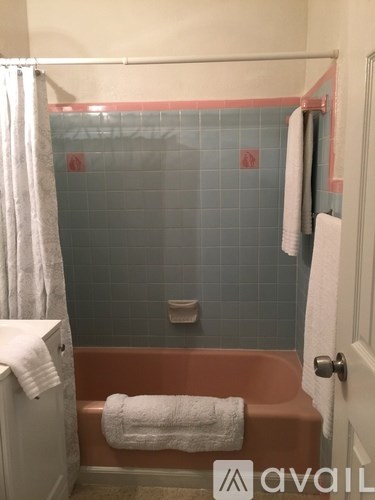 A bathroom with a white towel on the bathtub.