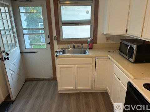 A kitchen with white cabinets and a black microwave.