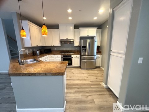 A kitchen with a brown counter top and white cabinets.