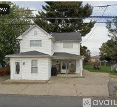 A white two-story house with a black roof and a small front porch.