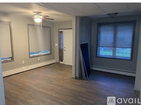 A spacious room with a ceiling fan and a door leading to another room.