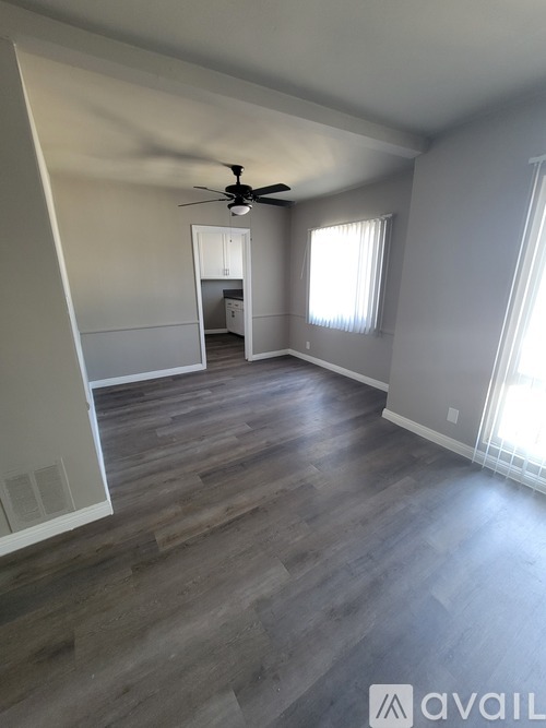 A room with a ceiling fan and wooden flooring.