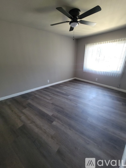 A room with a ceiling fan and wooden flooring.