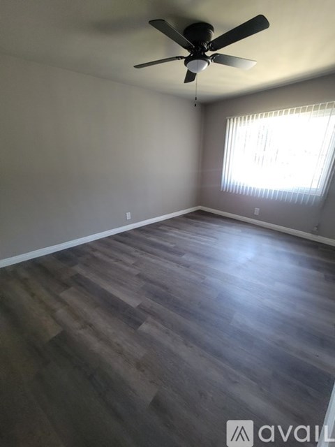 A room with a ceiling fan and wooden flooring.