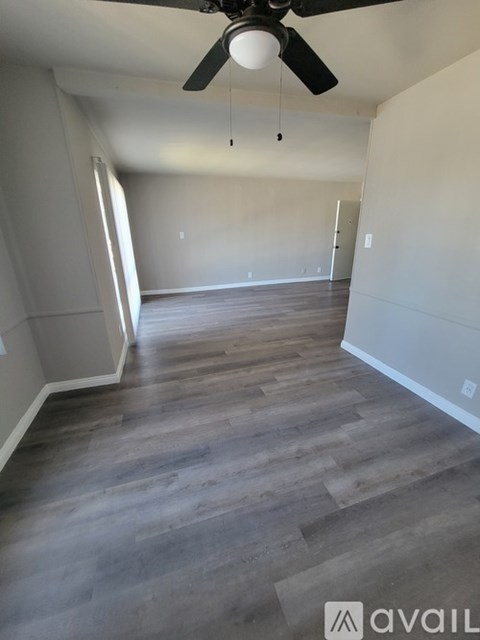 A room with a ceiling fan and wooden flooring.