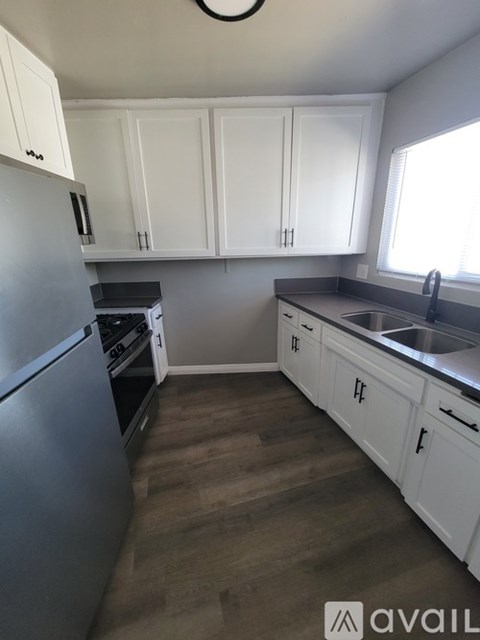 A kitchen with white cabinets and a stainless steel refrigerator.
