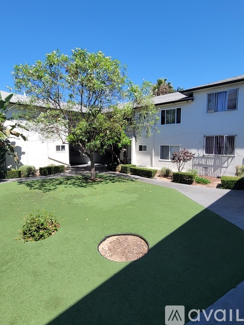 A white building with a green lawn and a baseball diamond in the front.