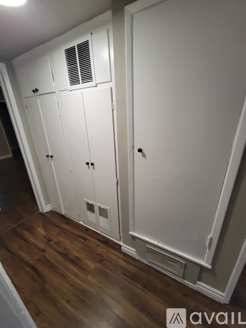 A white cabinet with a vent on top is in a room with wooden flooring.