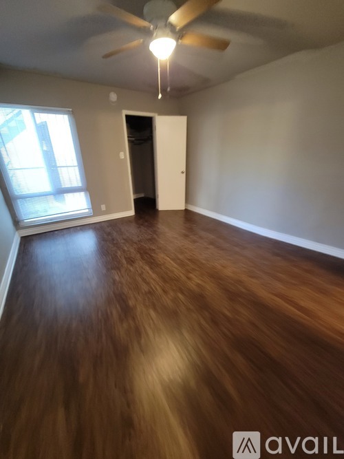 A room with a ceiling fan and wooden flooring.