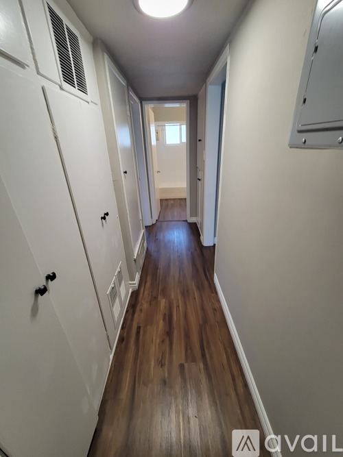 A long hallway with white walls and wood floors.
