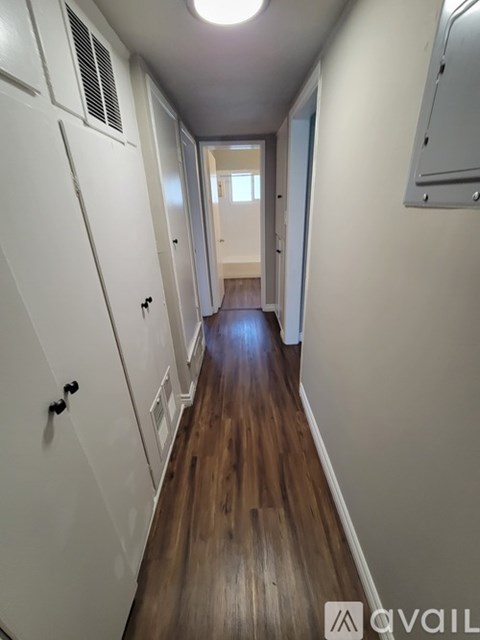 A long hallway with white walls and wood floors.