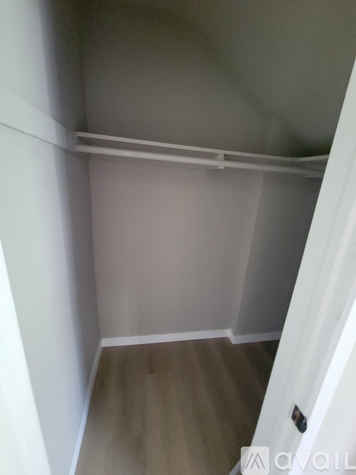 A white door is on the right side of a room with a wooden floor and white walls.