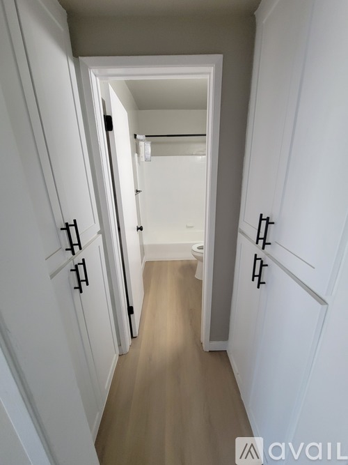 A long hallway with white doors and wood flooring.