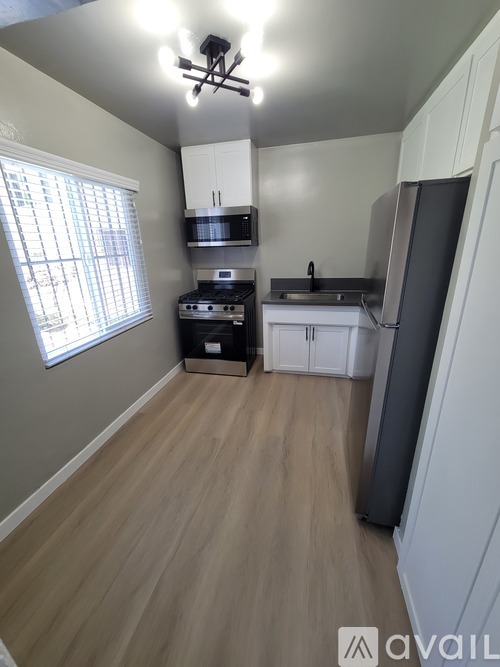 A kitchen with a refrigerator, sink, and stove.