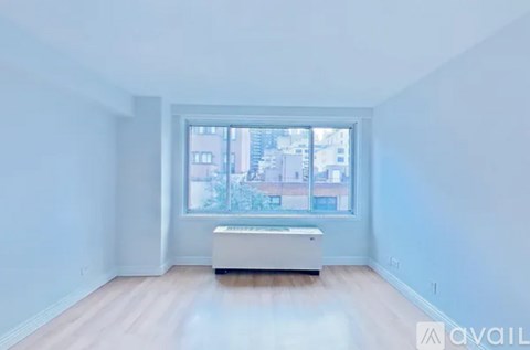 A large empty room with a window and a white couch.