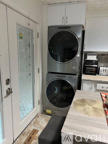 A washing machine is on top of a dryer in a kitchen.