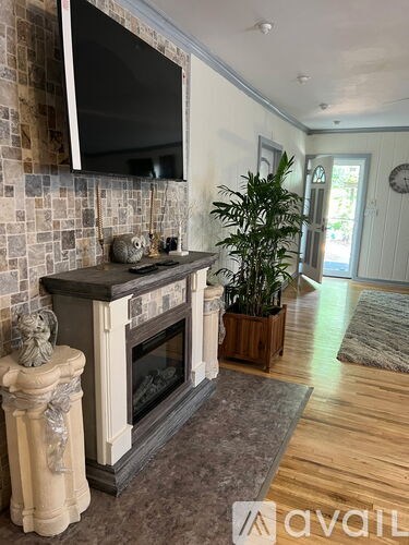 A living room with a fireplace and a television mounted above it.