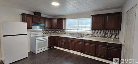 A kitchen with white appliances and brown cabinets.