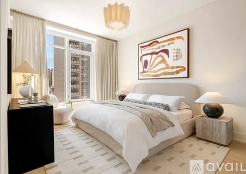 A bedroom with a large bed, a chandelier, and a painting on the wall.