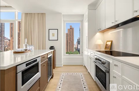 A kitchen with white cabinets and a view of a city skyline.
