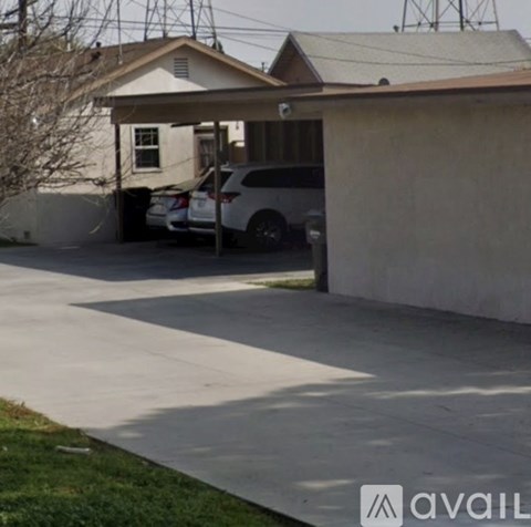 A car is parked in a driveway under a covered area.