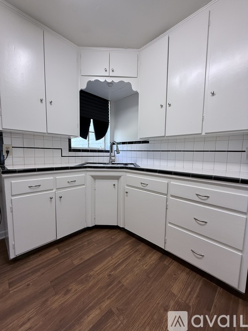 A kitchen with white cabinets and a black countertop.