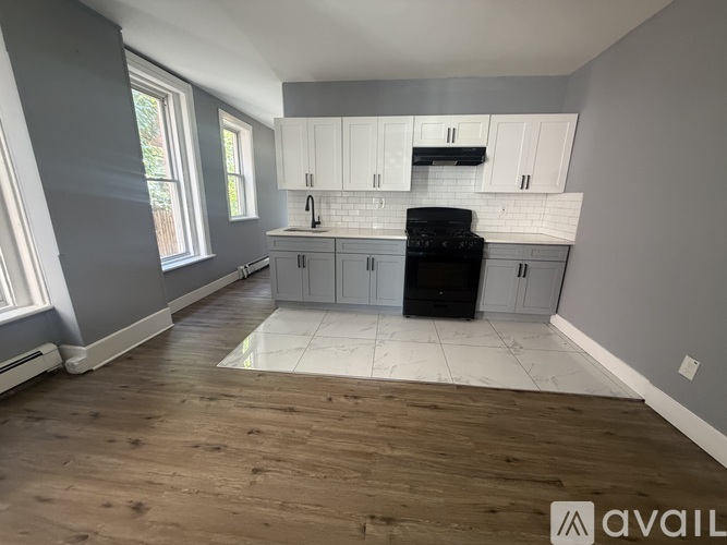 A kitchen with wooden floors and white cabinets.