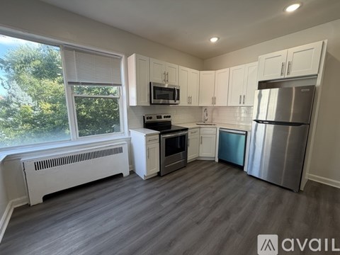 A kitchen with white cabinets and a window overlooking trees.