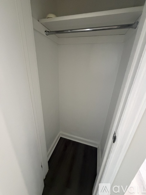 A small, white, enclosed space with a metal rail and a brown carpeted floor.