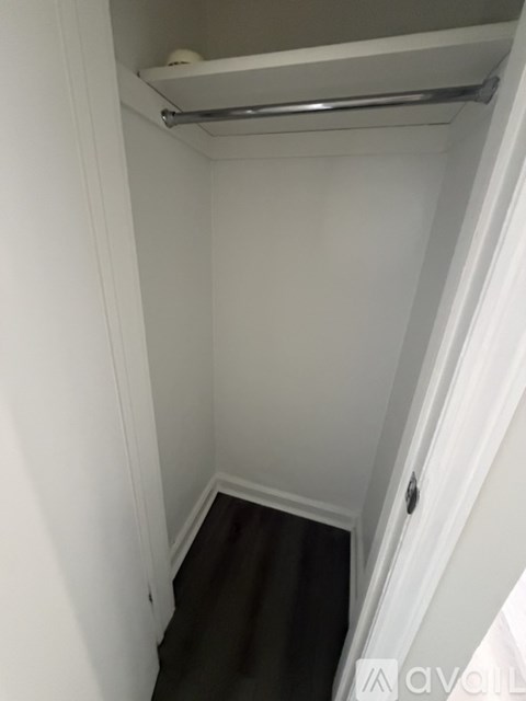 A small, white, enclosed space with a metal rail and a brown carpeted floor.