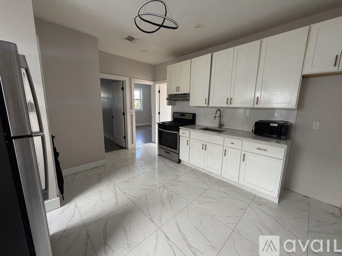 A kitchen with white cabinets and a marble floor.