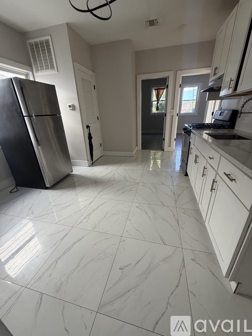 A kitchen with a black fridge and white cabinets.