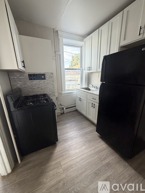 A black fridge and stove in a kitchen with white cabinets.