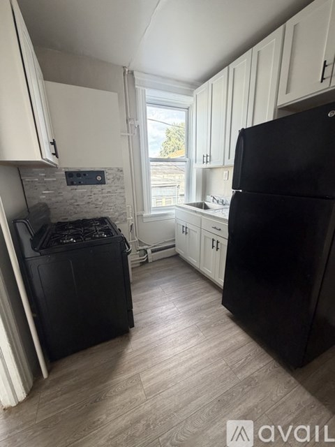 A black fridge and stove in a kitchen with white cabinets.