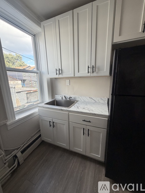 A kitchen with white cabinets and a black refrigerator.