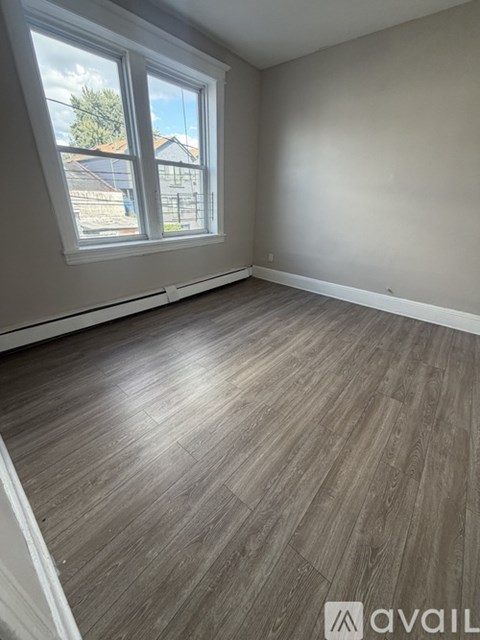 A room with a large window and wooden flooring.
