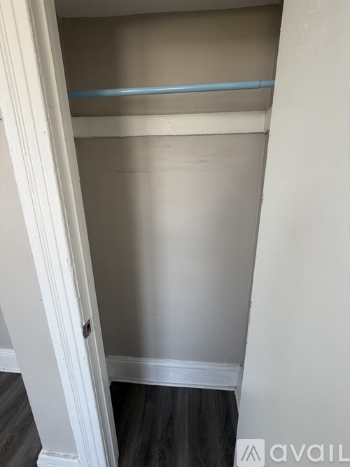 A small, empty closet with a blue shelf and a white door.