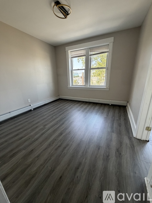 A room with wooden flooring and a window.