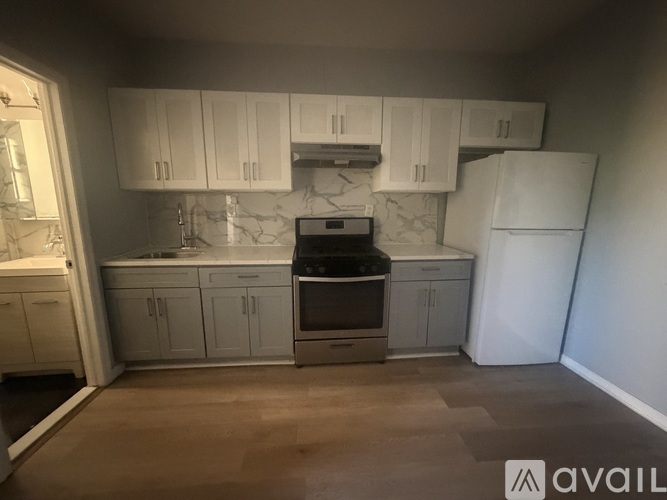 A kitchen with white cabinets and a marble backsplash.