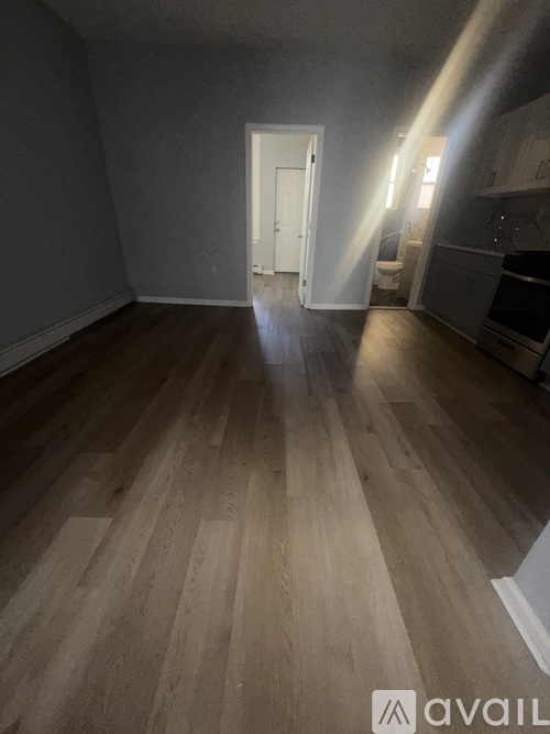 A room with wooden flooring and a doorway leading to another room.