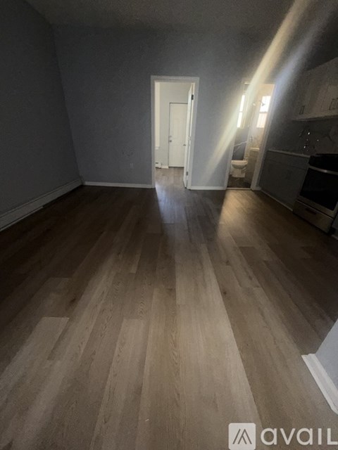 A room with wooden flooring and a doorway leading to another room.
