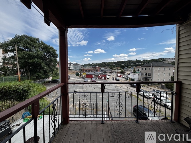 A balcony overlooks a parking lot and buildings.