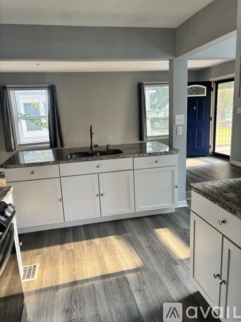 A kitchen with white cabinets and a black countertop.