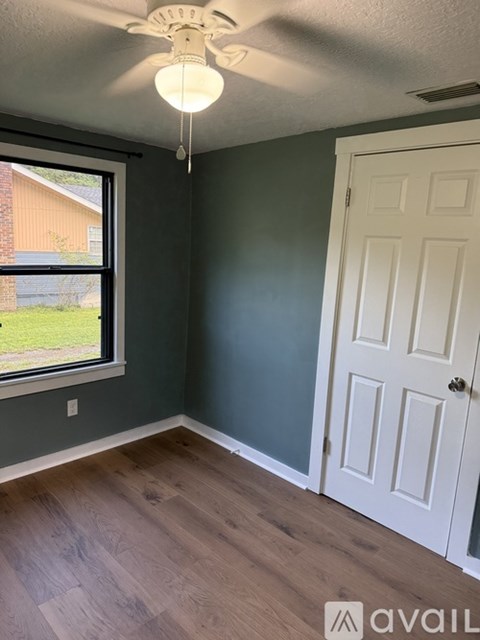 A room with a white door and a window with a view of a building outside.